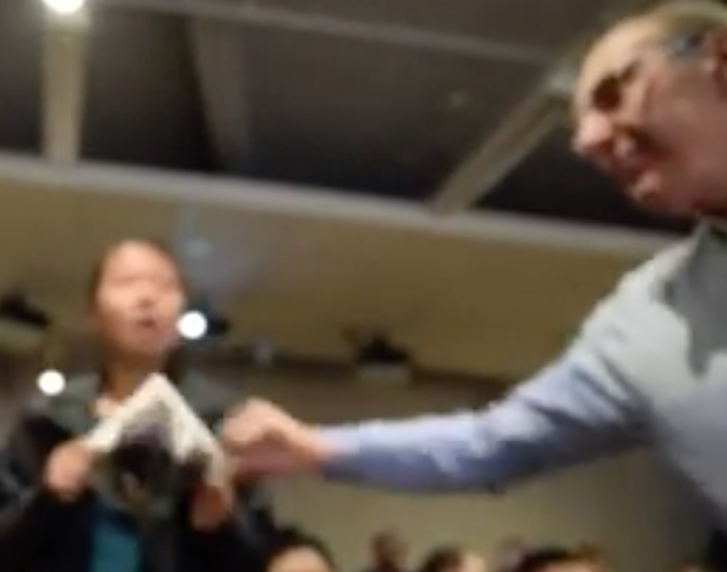 Angry audience member grabs poster out of activist's hands